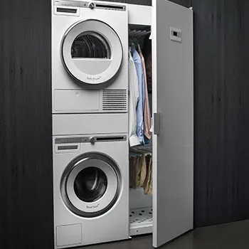 Tumble dryer stacked on a washing machine in a cupboard
